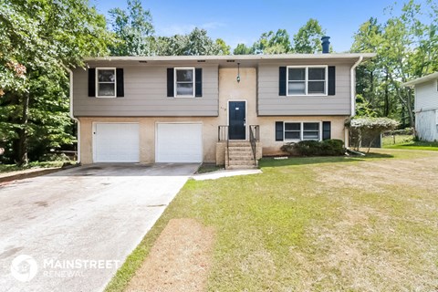 a beige house with two garage doors and a lawn